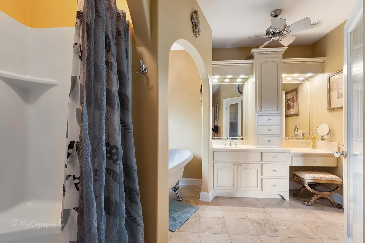 A luxurious bathroom featuring a freestanding bathtub, double vanity, decorative mirror, and a spacious shower area. The mood is calming and serene, with the layout making it perfect for both self-care routines and indulgent relaxation after a long day.