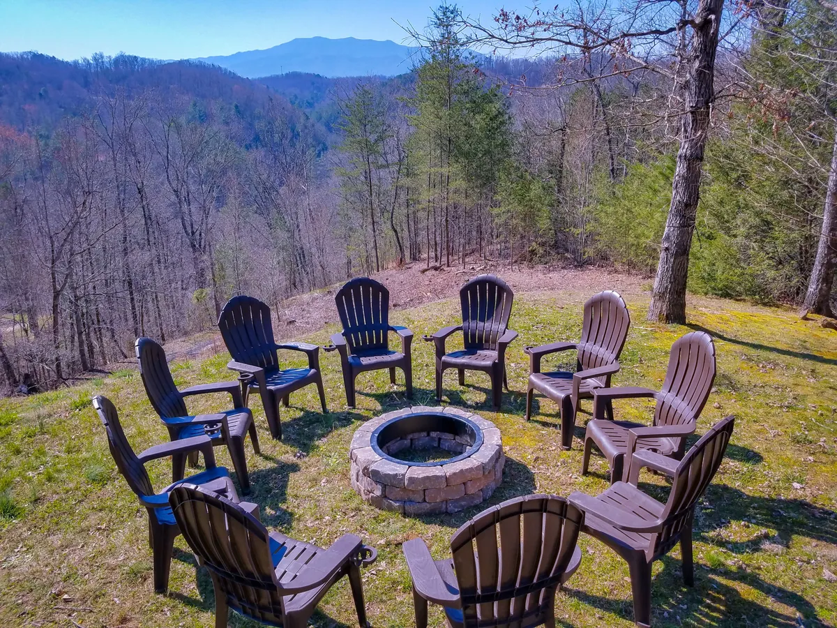 This exterior shot captures a circular seating arrangement around a fire pit with a scenic mountain view in the background. The space is designed for group gatherings, with ample seating and a panoramic vantage, suggesting opportunities for shared meals, conversations, and stargazing.