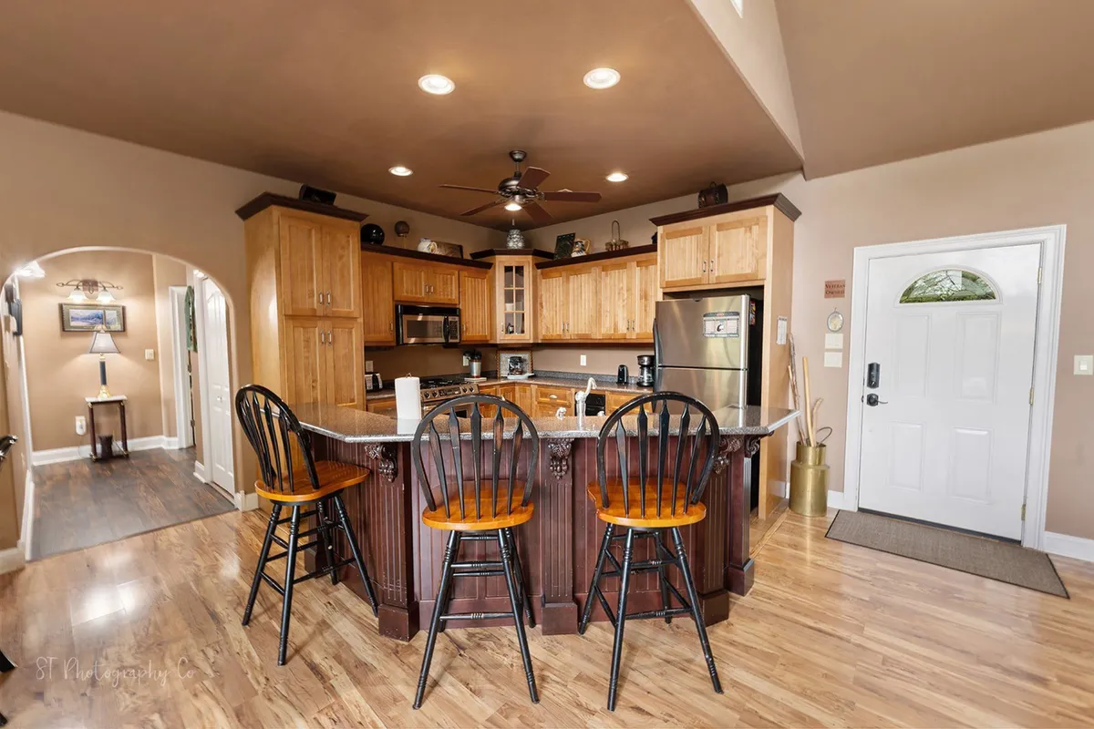 An inviting kitchen island is surrounded by wooden cabinetry and several bar stools, creating a warm, communal atmosphere ideal for casual gatherings or enjoying coffee at the breakfast bar.