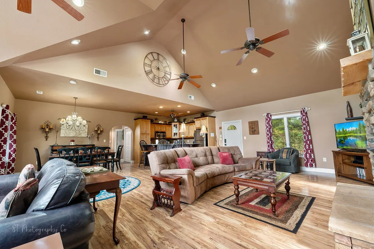 A welcoming open-plan space connects a spacious sofa, dining table, and kitchen area, all oriented around a fireplace. The arrangement encourages socializing and togetherness, emphasizing the fluid transition between living, dining, and kitchen spaces.