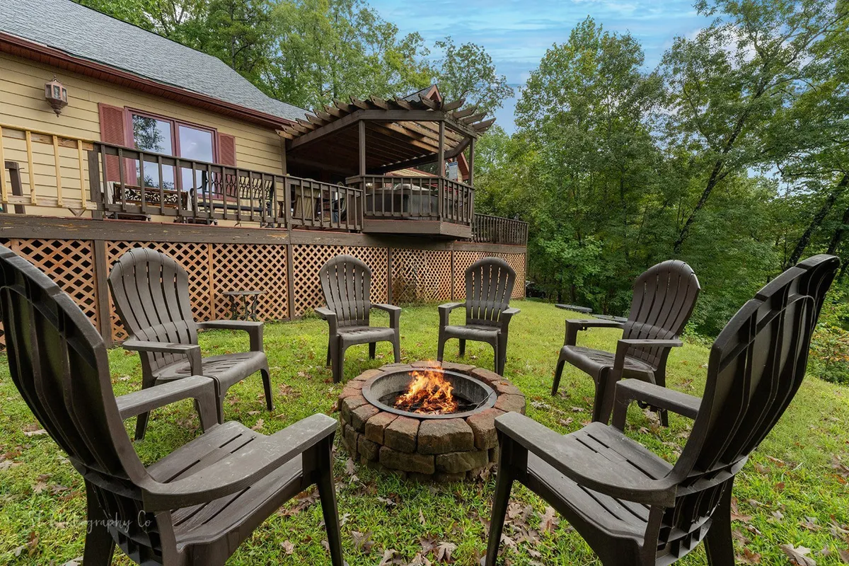 This exterior scene centers on a fire pit surrounded by ample outdoor seating and a spacious deck area. The mood is cozy and communal, inviting guests to gather, tell stories, or enjoy a cookout. The setting is adaptable for family s’mores sessions or romantic evenings by the fire.
