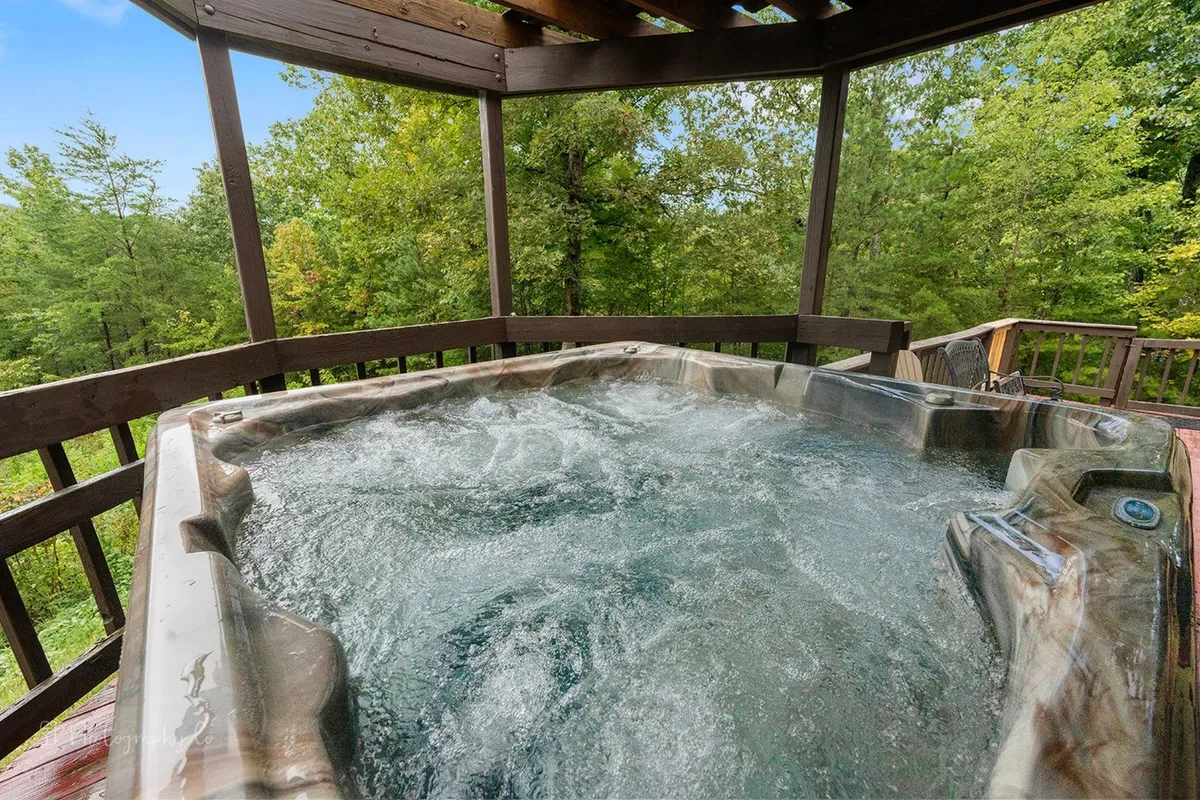 This image features a hot tub set on a wooden deck surrounded by lush greenery, offering a tranquil outdoor space to relax and unwind. The view gives a sense of privacy and natural beauty, connecting the home with its mountain surroundings.